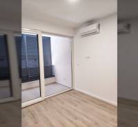 A room in a family house with air conditioning, wooden decor flooring, and sliding doors to the terrace.