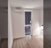 A room in a family house with a window, air conditioning, and a wooden decor floor.