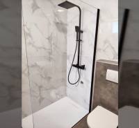 A shower enclosure and toilet in a family house with marble tiles.