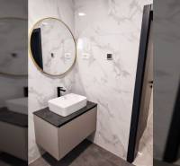 A bathroom in a family house with a sink on a cabinet, a mirror, and tiles with a marble pattern.
