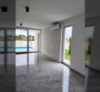 The interior of a family house with air conditioning, large windows, and a view of the pool.