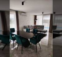 Dining room in a family house with a marble floor, dining table, and gray sofa.