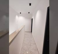 A narrow hallway in a family house with glossy tiles and white walls.