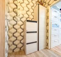 Wallpaper with a geometric pattern, white cabinets, and a wooden decor floor in a studio apartment.