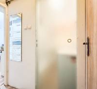 Sliding glass doors in a studio apartment with wood-patterned flooring and a wall mirror.