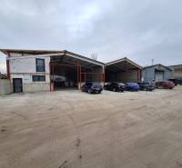 Warehouse and hall space on Strojnícka Street in Prešov with a parking lot and cars.