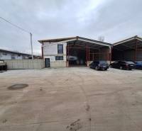 Industrial building on Strojnícka Street in Prešov with parking spaces and cars.