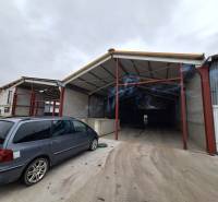 Warehouses and halls on Strojnícka Street in Prešov, a parking lot with vehicles in front of the entrance.