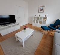 Living room in a three-room apartment with a wooden decor floor and simple furniture.