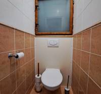 A toilet in a 3-room apartment with ceramic tiles and a toilet window.