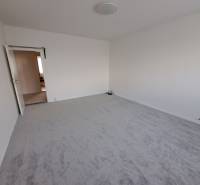 A bright room in a 3-room apartment with white walls and carpeted floor.