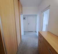 A hallway in a 3-room apartment with a built-in wardrobe and a chest of drawers with a wooden decor.