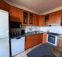 A kitchen in a 3-room apartment with corner cabinets and appliances, floor with wooden decor.