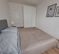Bedroom in a 3-room apartment with a bed, wardrobe, and floor with wooden decor.