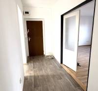 A hallway in a 3-room apartment with a wooden decor floor and white walls.