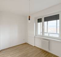 A bright room in a 3-room apartment, wooden decor flooring, radiator, window with a view.