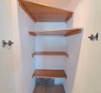 A wardrobe with built-in shelves in a 4-room apartment with a wood-patterned floor.
