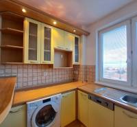 A kitchen in a 4-room apartment with a wooden decor, a sink, and a view from the window.