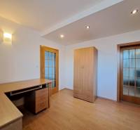 A room in a 4-room apartment with a wooden decor floor, a table, and a wardrobe.