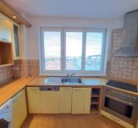 A kitchen in a 4-room apartment with a wood-patterned floor and a view of the city.