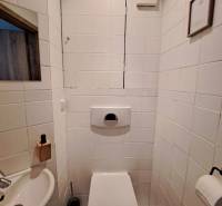 A bathroom with standard white tiles and a sink in a 4-room apartment.