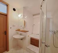 A bathroom in a 4-room apartment with a bathtub, a shower, and white tiles.