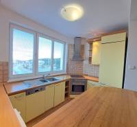 A kitchen in a 4-room apartment with a wooden decor floor and yellow cabinets.