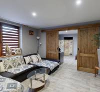Living room with a comfortable sofa, sliding doors, and a wooden-patterned floor.