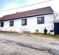 A family house in Unín with a white facade, a brown roof, and an access road.