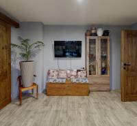 A room in a family house with a wooden decor floor, a television, and decorative elements.