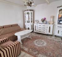 Living room of a family house with a striped sofa and white cabinets.