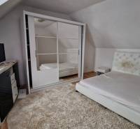 A bright bedroom with a bed, wardrobe, and carpet in a family house.