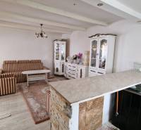 Living room in a family house with striped furniture, a decorative cabinet, and a wooden-patterned floor.