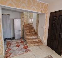 Interior of a family house with a staircase, refrigerator, and decorative wallpaper.
