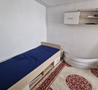 A simple room with a bed and a shelf in a family house.