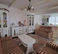 Living room in a family house with sofas, wooden cabinets, and a carpet.