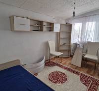 A room in a family house with a bed, shelves, and a floor with a wooden decor.