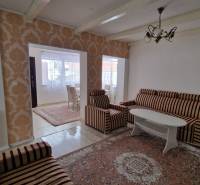 A living room in a family house with patterned wallpaper and striped furniture.