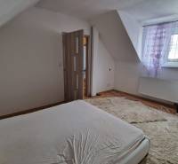 A bedroom in a family house with a wooden decor floor and a light carpeted area.
