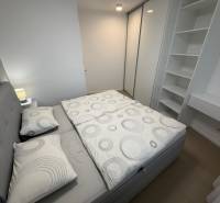 Bedroom in a two-room apartment with wood-patterned flooring and practical storage spaces.