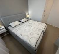 Bedroom with a double bed and a wood-patterned floor in a two-room apartment.