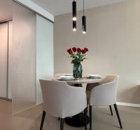 Dining area with a table and chairs, wooden decor flooring in a 2-room apartment.
