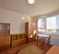 A studio apartment with furniture, a table, and chairs, complemented by a floor with a wooden decor.
