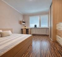 Bedroom in a 4-room apartment with wood-patterned flooring and built-in furniture.