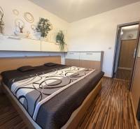 Bedroom with built-in wardrobes and a bed in a 4-room apartment with a wooden decor.