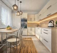 Kitchen in a 4-room apartment with a large window, wooden decor flooring, and a dining table.