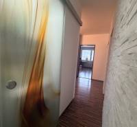 A hallway with a wooden decor floor and interesting sliding doors in a 4-room apartment.