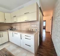 A kitchen in a 4-room apartment with a wooden decor floor and light cabinets.