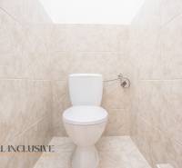 A restroom tiled with light tiles in a building.