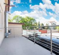 A balcony in Dunajská Streda with a view of the surrounding buildings and park.
